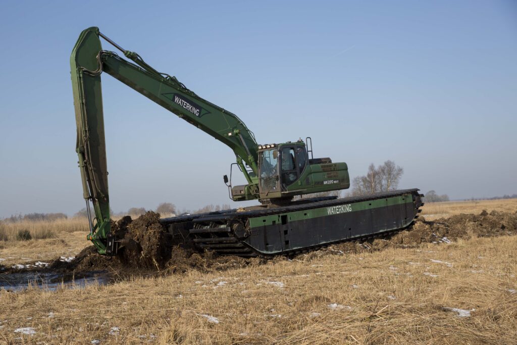 Natuurherstel en Waterbouw - natuurherstelproject referentie project - Zicht: WK220 NG-5 werkzaam in winters landschap natuurherstelwerkzaamheden uitvoeren