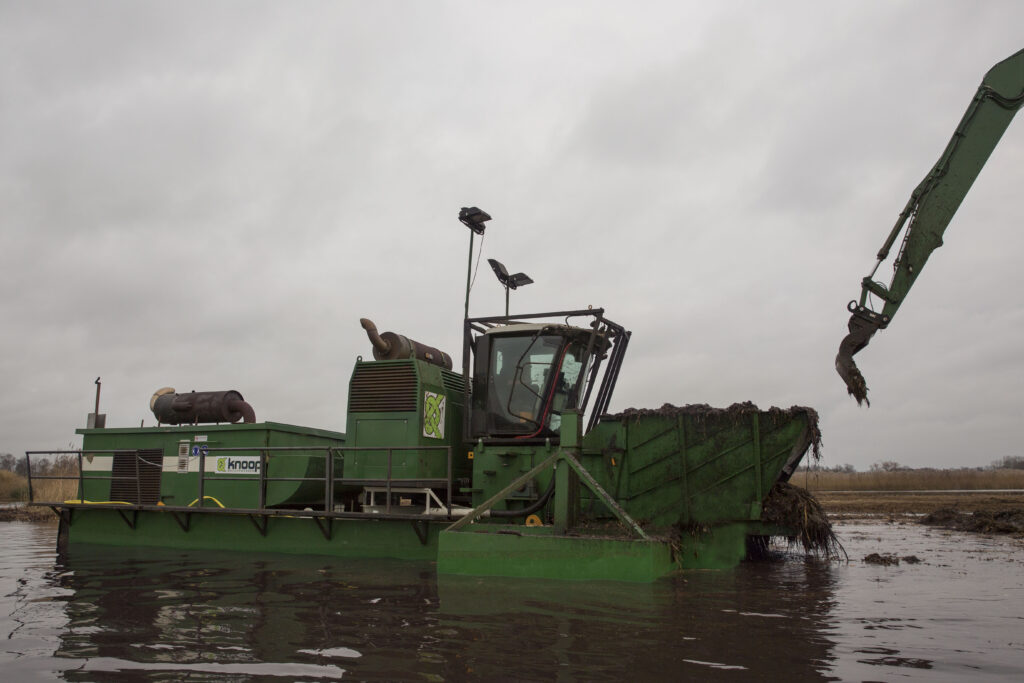 Natuurherstel en Waterbouw - natuurherstelproject referentie project - Zicht: zijaanzicht van afstand werkzaamheden shredder dredger & WK220 NG-5 in het water