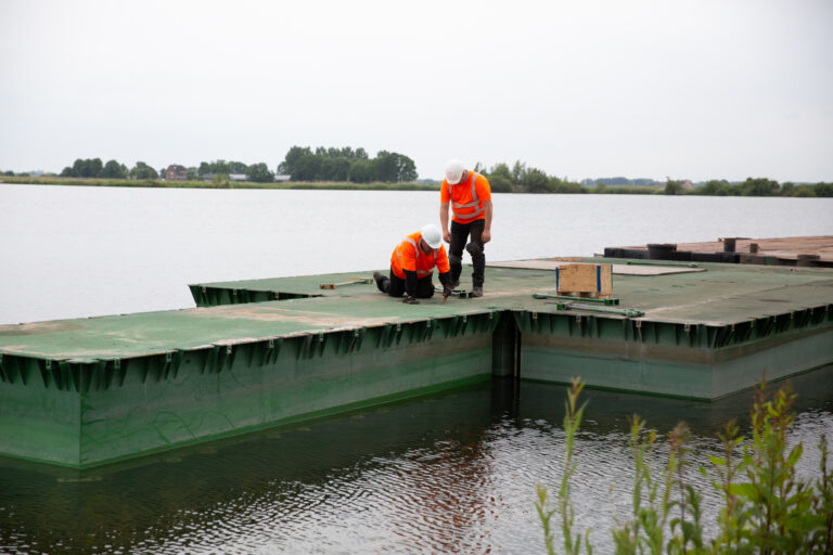 Verankeringssystemen - Opbouw verankeringsplatform voor verankeringssysteem. Zicht; Drijvende pontons, in elkaar gezette pontons, samenwerkingen, voorbereidingen van twee personeelsleden