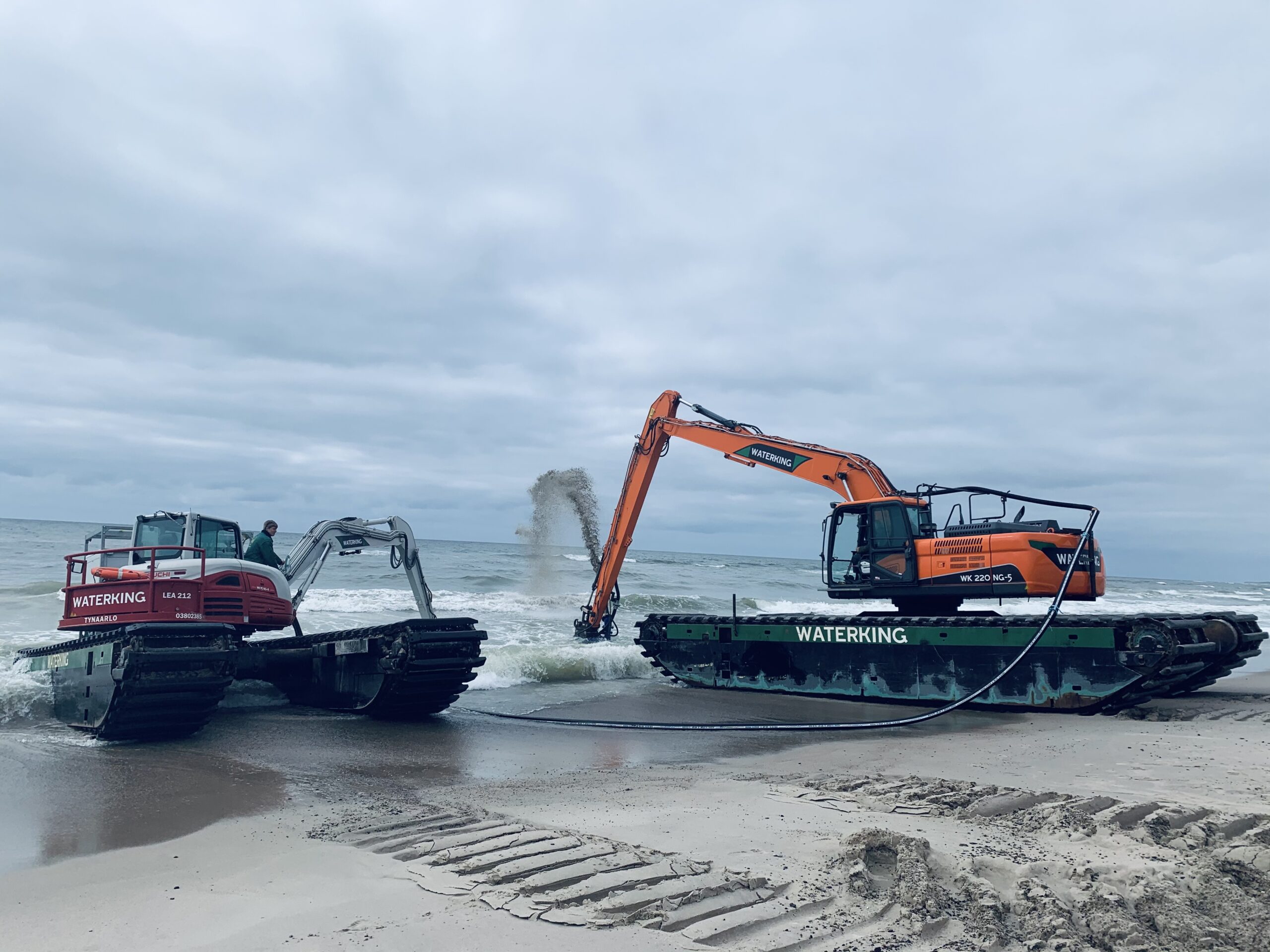Natuurherstel en Waterbouw, Rental Referentie, Zicht: WK220 NG-5 & WK95 NG-A werkzaam in het water zichtbaar vanaf het strand Hesse Denemarken Viking Link Project semi-achter aanzicht