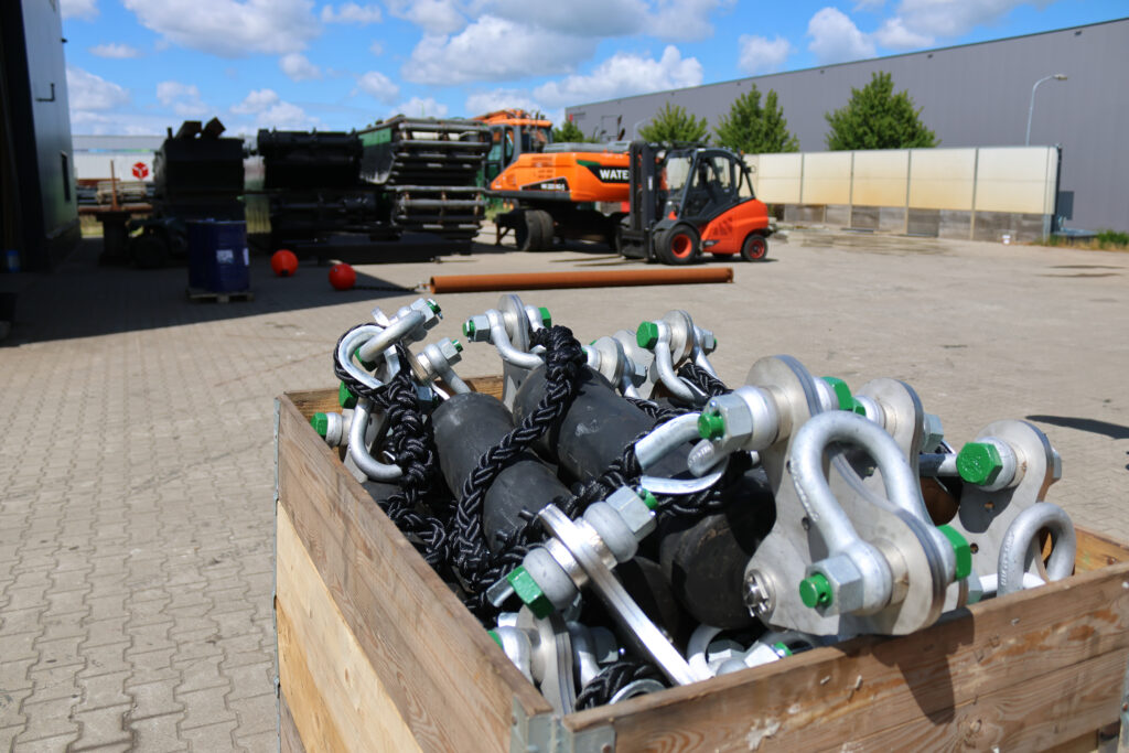 Transport vanaf de dam Tynaarlo naar project in Cottbus (DE) met zicht op anker & boeien in de achtergrond. Voorgrond schok-bestendige-onderdelen van de wavebarriere