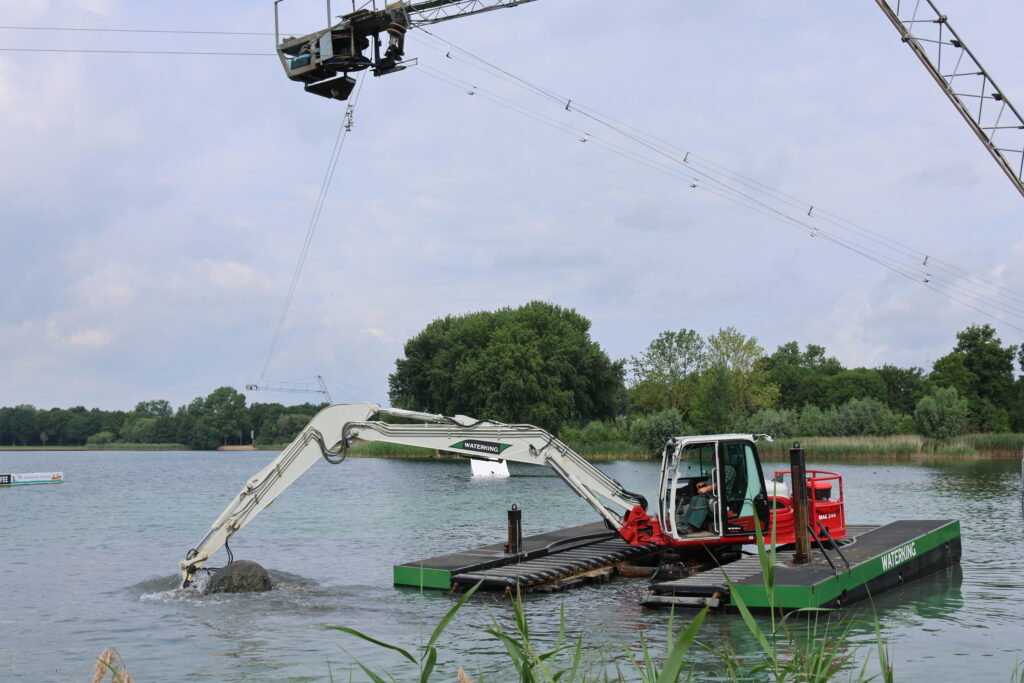 WK95 NG-A incl. zijpontons aanwezig op kabelwaterskibaan Braamt voor onderhoudswerkzaamheden - Vooraanzicht van de machine op het water onder de kabels van de kabelwaterskibaan